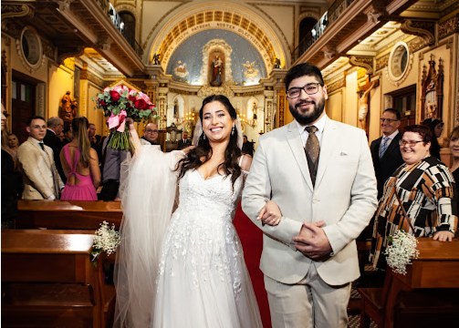 Noivos saindo da igreja de mãos dadas, ela erguendo o buquê, cercados por convidados aplaudindo.